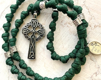 May include: A green paracord rosary with a silver Celtic cross pendant and a silver charm that says "Pray for Us".