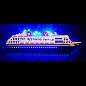 May include: A white and black cruise ship with the text "THE STEPHENS FAMILY" on the side. The ship is illuminated with blue lights and has two red Mickey Mouse heads on the top.