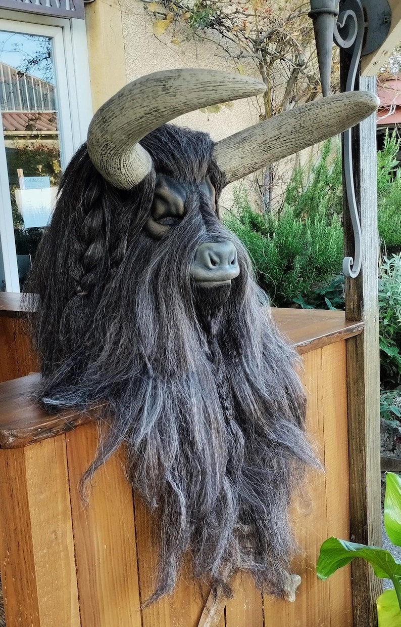 May include: A large, detailed, grey and black bull mask with long, shaggy hair. The mask has a realistic appearance and is made of a durable material.