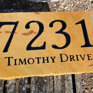 May include: A brown stone house number sign with black painted numbers "7231" and the text "TIMOTHY DRIVE".