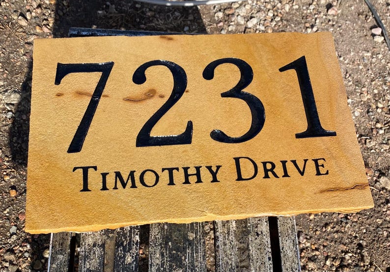 May include: A brown stone house number sign with black painted numbers "7231" and the text "TIMOTHY DRIVE".