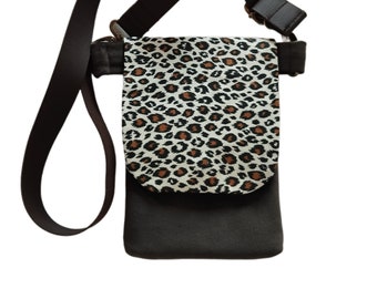 May include: A brown crossbody bag with a leopard print flap. The bag has a long adjustable strap.