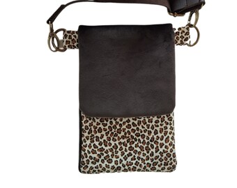 May include: A brown leather crossbody bag with a leopard print flap. The bag has a long adjustable strap and a metal clasp.