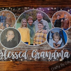May include: A jigsaw puzzle with a woodgrain background and a collage of family photos. The puzzle features a variety of people, including children, adults, and seniors. The puzzle is titled "Blessed Grandma" and has a "Crafty By Day Designs" logo in the bottom right corner.