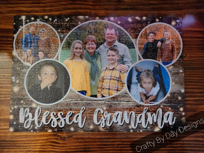 May include: A jigsaw puzzle with a woodgrain background and a collage of family photos. The puzzle features a variety of people, including children, adults, and seniors. The puzzle is titled "Blessed Grandma" and has a "Crafty By Day Designs" logo in the bottom right corner.