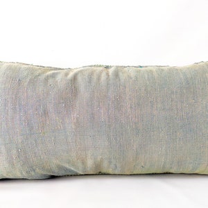 May include: A rectangular, light blue decorative pillow with a textured fabric. The pillow has a faded appearance with hints of green and blue. The edges are finished with green stitching. This pillow is perfect for adding a touch of color to any room.