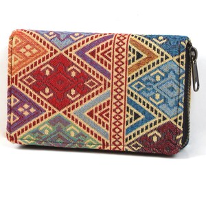 May include: A rectangular wallet with a colourful geometric pattern. The wallet has a zip closure and a vibrant design with red, blue, orange, and purple hues. The wallet is likely made of woven fabric.