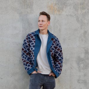 Peut inclure: Un homme portant une veste en jean bleue avec un motif blanc et bleu. La veste a une fermeture &eacute;clair et un col montant.