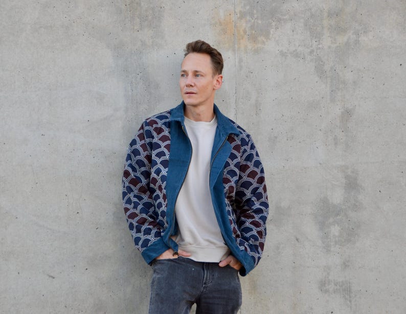 Peut inclure: Un homme portant une veste en jean bleue avec un motif blanc et bleu. La veste a une fermeture &eacute;clair et un col montant.