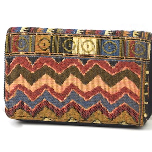 May include: A colourful zippered wallet with a geometric pattern in shades of brown, red, blue, and beige. The wallet has a zipper closure and a woven fabric design.