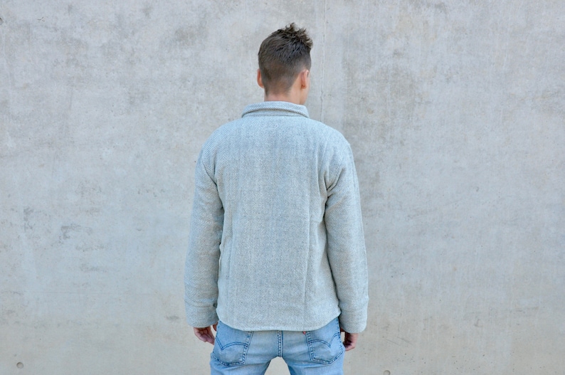 Puede incluir: Una camisa de manga larga de color gris claro con cuello abotonado. La camisa est&aacute; hecha de una tela suave y texturizada.