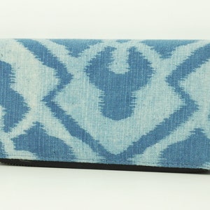 Peut inclure: Un portefeuille zippé à motif bleu et blanc. Le portefeuille est fait d'un tissu doux et texturé.