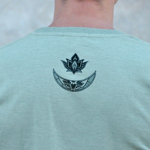 May include: A light green t-shirt with a black and white graphic of a crescent moon and a lotus flower.