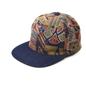 Puede incluir: Una gorra de béisbol de color azul y con un patrón multicolor con una visera azul marino.
