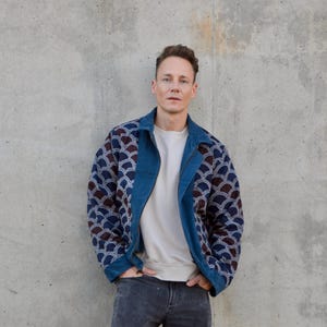 Peut inclure: Un homme portant une veste en jean bleue avec une doublure &agrave; motifs blancs et bleus. La veste a une fermeture &eacute;clair et un col. L'homme porte un t-shirt blanc sous la veste et un jean bleu.