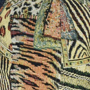May include: Close-up of a patterned fabric with a mix of animal print and geometric designs. The fabric features a combination of yellow, black, orange, and green colors, creating a textured and vibrant appearance. The design includes leopard spots and zebra stripes.