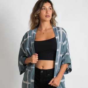 Könnte beinhalten: Eine Frau trägt einen blau-weiß karierten Kimono mit einem schwarzen Tanktop und schwarzen Jeans-Shorts.