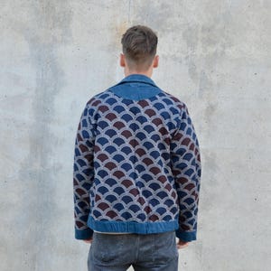 Peut inclure: Une veste en jean bleue avec un motif g&eacute;om&eacute;trique brun et bleu. La veste a un col et une fermeture &eacute;clair.
