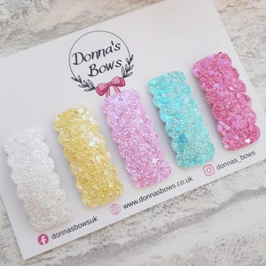 May include: Five glitter hair clips in white, yellow, pink, turquoise, and pink, displayed on a card. The card features the text "Donna's Bows" and social media details. Each clip is approximately 5 cm in length.