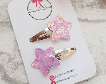 May include: Two pink glitter star hair clips with silver metal clips. The clips are on a white card with the text "Donna's Bows" and social media handles @donnas_bows and @donnasbowsuk.