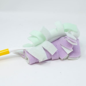 May include: A yellow handled cleaning tool with a white, light green, and purple microfiber cleaning head.