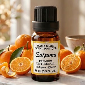 May include: A brown glass bottle of Satsuma premium diffuser oil with a black cap, surrounded by fresh oranges and orange slices. The label reads "MAMA BEARS SCENT BOUTIQUE" and "15 ml (0.5 FL. OZ.)".