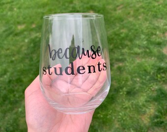 May include: Clear glass wine glass with the text "because students" printed in black on the side.