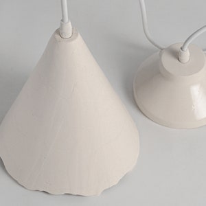 Handcrafted ceramic hanging light fixture for kitchen island with warm diffused lighting effect. White ceramic pendant light fixtures with a simple design. Thefixture is cone-shaped.