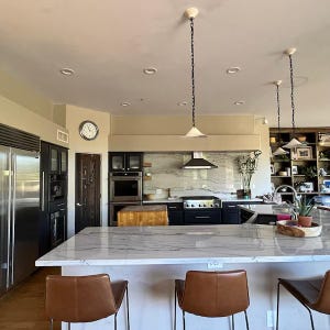 3 ceramic pendants lamps whith a chains hanging in modern skandi kitchen under kitchen island and dinner table.