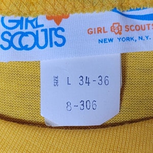 May include: White tag with blue text that reads "Girl Scouts" and "New York, N.Y."  A smaller white tag with black text reads "Size L 34-36 8-306".