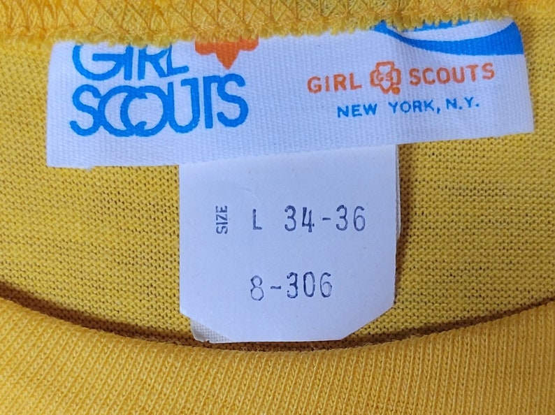 May include: White tag with blue text that reads "Girl Scouts" and "New York, N.Y."  A smaller white tag with black text reads "Size L 34-36 8-306".