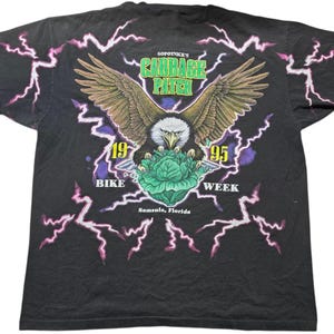 May include: Black t-shirt with a graphic of a bald eagle holding a cabbage. The text "Sopotnick's Cabbage Patch 1995 Bike Week Samsula, Florida" is printed on the shirt.