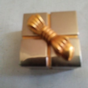 May include: A small, gold-colored gift box with a gold bow on top.