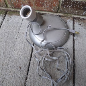 May include: A silver-colored electrical outlet with a white porcelain light socket and a gray electrical cord.