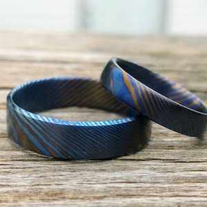 Könnte beinhalten: Zwei Ringe aus Metall mit einem blauen und goldenen Muster. Die Ringe liegen übereinander.
