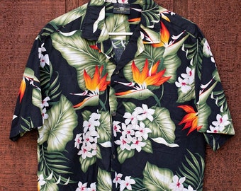 May include: A black short-sleeved button-down shirt with a tropical print featuring green leaves, orange and white flowers, and a bird of paradise design.