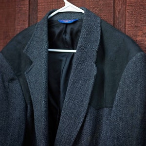 May include: A gray tweed blazer with suede elbow patches. The blazer has a black lining and a single button closure.