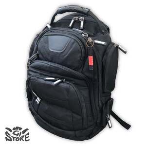 May include: A black backpack featuring multiple zippered compartments, a reinforced top handle, and adjustable shoulder straps. The bag includes a small red and black keychain accessory attached to a zipper pull and the text GI STORE in the corner.