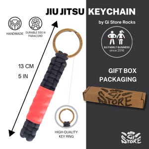 May include: A black and red paracord keychain with a bronze-colored metal ring. The keychain measures 5 inches in length. Text on the image includes JIU JITSU KEYCHAIN, by Gi Store Rocks, BJJ FAMILY BUSINESS since 2016, and GIFT BOX PACKAGING.