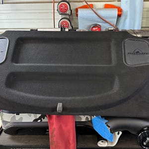 May include: Black carpeted cargo cover with two black speaker covers that say "Rotary" in white lettering.