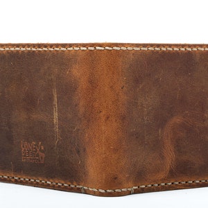 May include: A brown leather wallet with white stitching and the text "Lone Deer" embossed on the front.