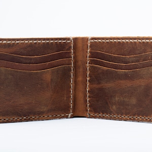May include: A brown leather wallet with multiple card slots and a billfold. The wallet is open and the interior is visible.