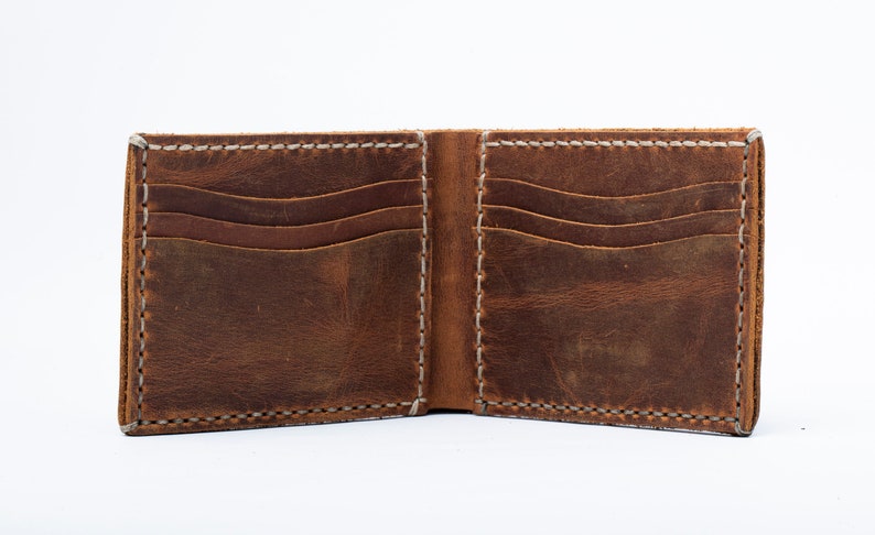 May include: A brown leather wallet with multiple card slots and a billfold. The wallet is open and the interior is visible.