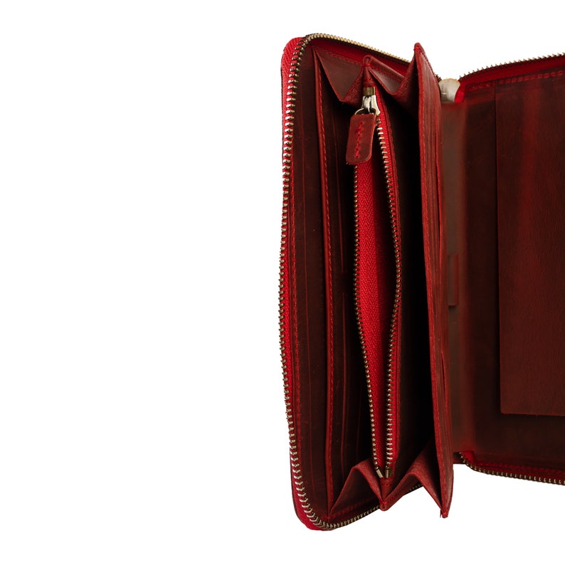 May include: A red leather zippered wallet with a gold zipper. The wallet is open and the inside is visible.