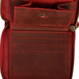 May include: Red leather wallet with a zipper closure and multiple card slots. The wallet is open and empty.
