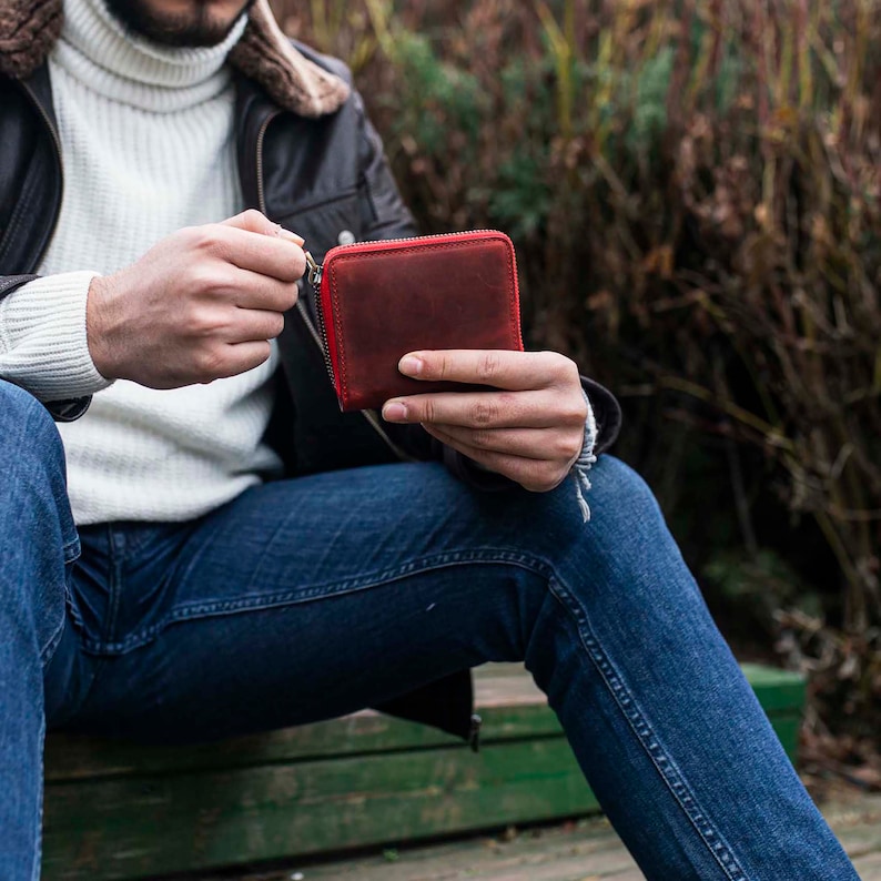 May include: A red leather zippered wallet with a brown leather exterior.