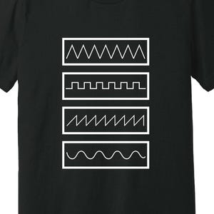 May include: Black t-shirt with a white graphic design. The design features four rectangular boxes, each containing a different white line pattern: a zigzag, a stepped line, another zigzag, and a wavy line. The shirt has a crew neck and short sleeves.