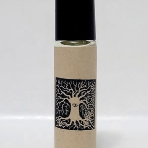 May include: A small, clear glass bottle with a black roll-on top. The bottle has a brown paper label with a black and white illustration of a tree with an eye in the center.