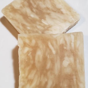 May include: Two bars of handmade soap, one on top of the other. The soap is a light beige color with a marbled pattern.