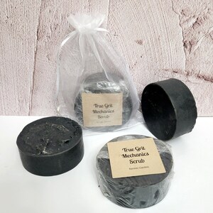 May include: Three black bars of soap with a white label that reads "True Grit Mechanics Scrub" and "Karmic Garden".